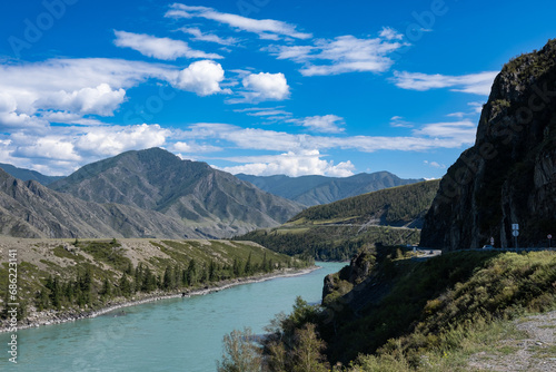 Beautiful mountain landscape with a river on a bright sunny day. White clouds in a blue sky. The Katun River in the Altai Republic, part of the Chui tract