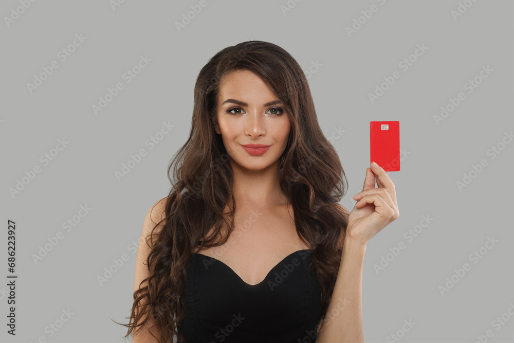 Portrait of lovely cheerful woman holding in hands demonstrating bank card solution isolated over grey color background Portrait of lovely cheerful woman holding in hands demonstrating bank card solution isolated over grey color background