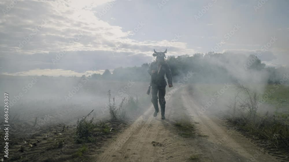 the monster walking along the road has a scary cow mask and the uniform of a German Wehrmacht soldier on his head the monster walking along the road has a scary cow mask and the uniform of a German Wehrmacht soldier on his head