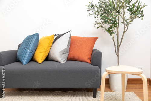 Modern interior design of living room with blue, yellow and orange pillow. Grey sofa with wood coffee table.