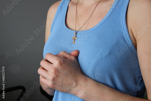 Woman with golden christian cross folded her arms in prayer