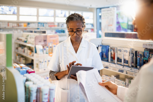 Senior female pharmacist doing inventory with colleague at drugstore photo