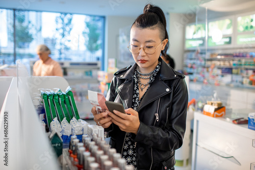 Young woman reading ingredients of skin care product while shopping at the drugstore photo