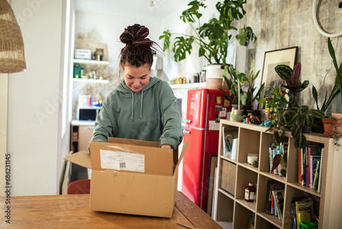 Young Woman Unboxing Parcel in Kitchen photo