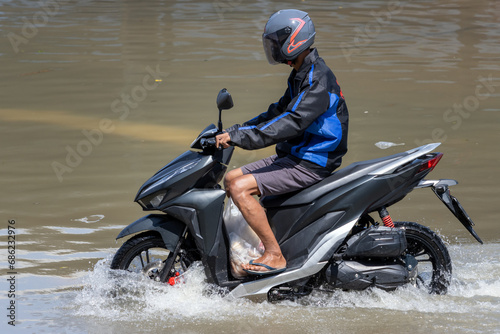 A motorbike rides on a flooded street, Bangkok, Thailand