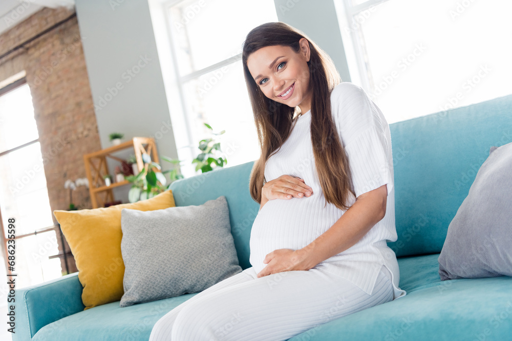 Photo of adorable pretty lovely cute girl dressed pajama sitting on couch hands touching belly beautiful time moment indoors Photo of adorable pretty lovely cute girl dressed pajama sitting on couch hands touching belly beautiful time moment indoors