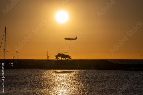 Coucher de soleil en bord de mer, sur un phare, avec le passage d'un avion