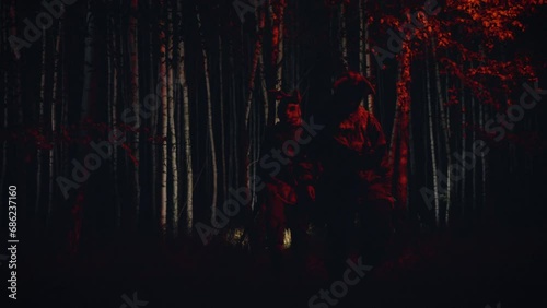 Soldier in a scary mask. warrior in a dark forest with a scary mask on his head. illuminated with red and white light. Horror

