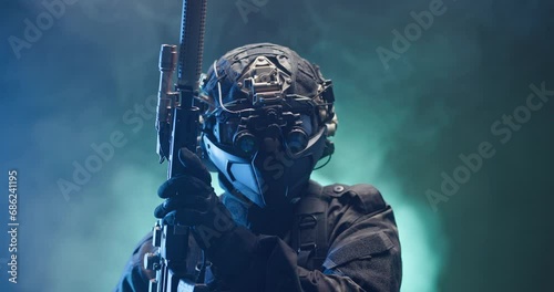 Soldier fully equipped with tactical gear and protection aiming his rifle at enemy with blue and green smoke in the background. photo