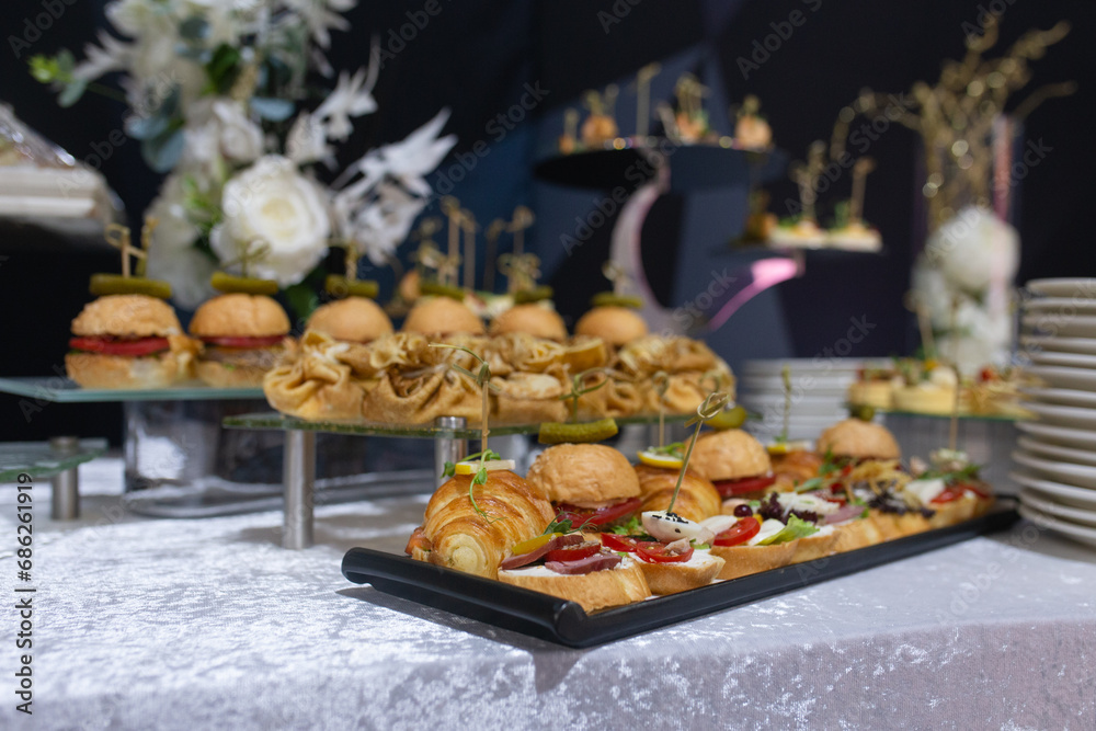 Croissants, burgers and various snacks on stands on the buffet table