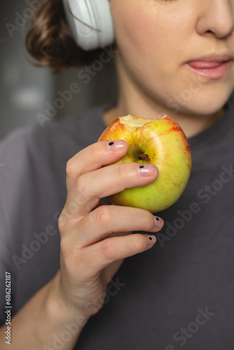 Woman eats an apple at home as a healthy snack between work.