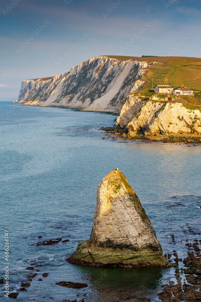 Fototapeta premium Early morning light hitting the Stag Rock at Freshwater Bay, with the white chalk cliffs of Tennyson Down in the background, Isle of Wight.