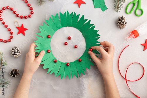 Christmas wreath from color paper with children. Step by step instructions. Handmade DIY new year holiday decoration project.