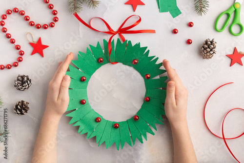 Christmas wreath from color paper with children. Step by step instructions. Handmade DIY new year holiday decoration project.