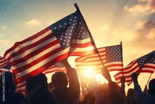 A group of people holding American flags against the backdrop of a beautiful sunset. This image can be used to represent patriotism, unity, or celebrations of national holidays.