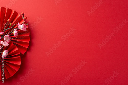 Embrace tradition in a festive top view display featuring paper fans and sakura blossom on a red backdrop. Perfect for messaging or advertisements photo