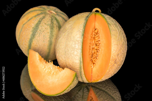Two melons and one slice in focus, close-up, on a black background.