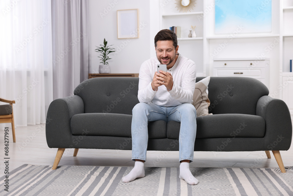 Happy man having video chat via smartphone at home Happy man having video chat via smartphone at home