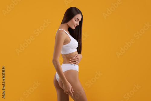 Young woman in stylish white bikini on orange background