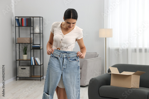 Young woman with just unpacked new jeans at home, space for text. Online shopping