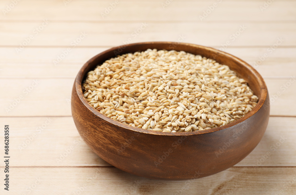 Dry pearl barley in bowl on light wooden table Dry pearl barley in bowl on light wooden table