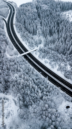 Landstraße durch verschneiten Wald im tiefsten Winter