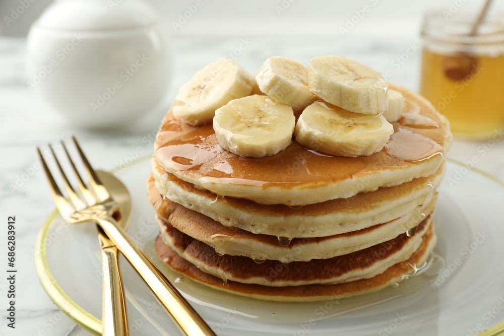 Delicious pancakes with bananas and honey on white table, closeup Delicious pancakes with bananas and honey on white table, closeup
