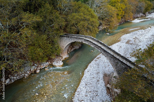 Drone aerial of Ancient, stoned, arched bridge St. Vissarion on the Portaikos river in autumn. Trikalla pyli village Thessaly Greece