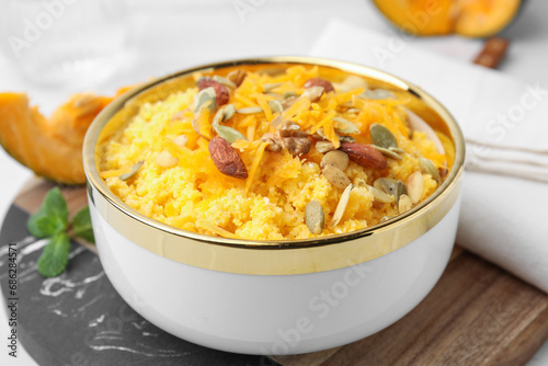 Tasty cornmeal with nuts, pumpkin and seeds in bowl on table, closeup