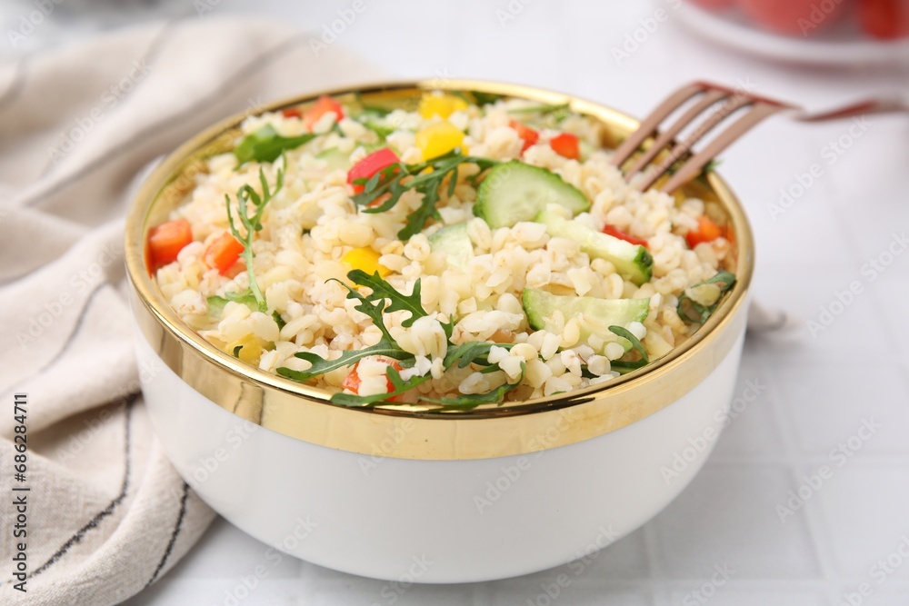Cooked bulgur with vegetables in bowl on white tiled table, closeup Cooked bulgur with vegetables in bowl on white tiled table, closeup