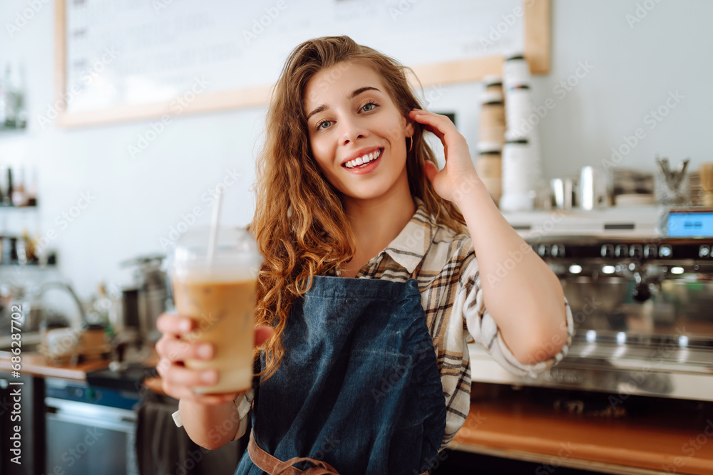Portrait of a smiling female barista with a takeaway drink standing behind a bar counter. Business concept, food and drinks. Portrait of a smiling female barista with a takeaway drink standing behind a bar counter. Business concept, food and drinks.