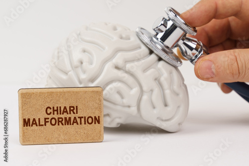 Using a stethoscope, the brain is diagnosed, next to it is a sign with the inscription - Chiari malformation