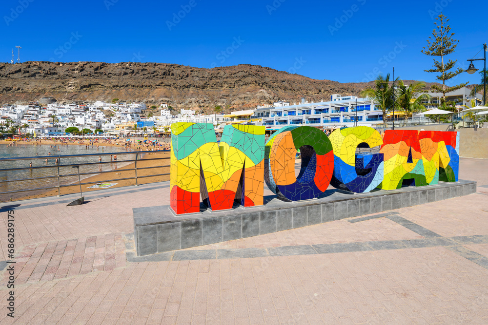 The colorful letters and text welcome sign for the picturesque fishing village of Puerto de Mogan, Spain, on the island of Gran Canaria, Canary Islands.