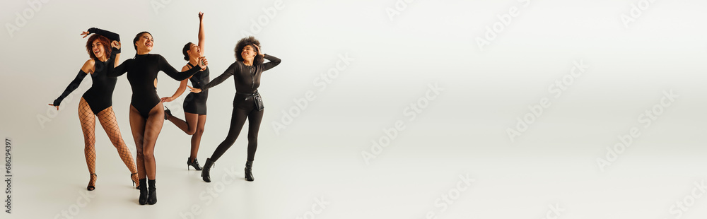 Fototapeta premium jolly african american female friends in sexy bodysuits dancing happily, fashion concept, banner