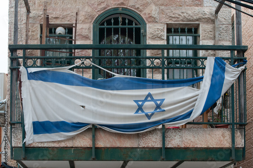 Tattered flag of Israeli draped across a Jerusalem balcony