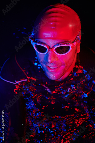 authentic triathlete swimmer having a break during hard training on night neon gel light © .shock