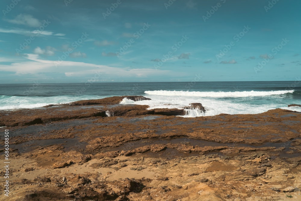 rocky shoreline with dark brown and red geological makeup where the tidal lines are visible at the edge of where waves crash and splash the rocks, keeping them moist with salty ocean water rocky shoreline with dark brown and red geological makeup where the tidal lines are visible at the edge of where waves crash and splash the rocks, keeping them moist with salty ocean water
