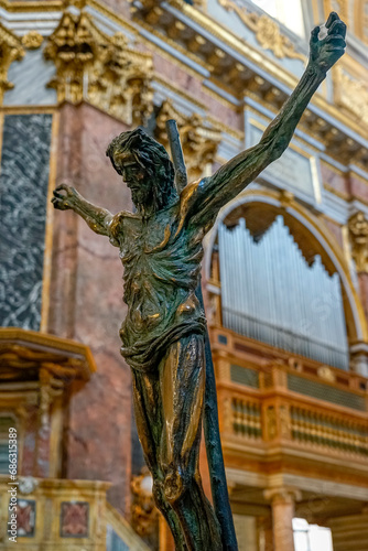 statue of crucified jesus christ with the background of organ pipes inside the basilica SS Ambrogio e Carlo