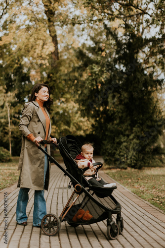 Young woman with cute baby girl in baby stroller at the autumn park © BGStock72