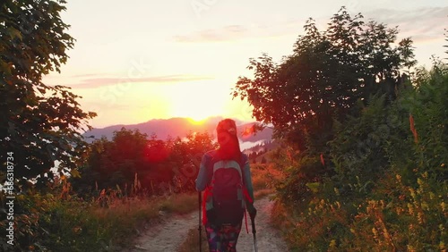 Millenial young hiker woman enjoy hike use poles nordic walk on forest trail on hilltop on sunset by greenery outdoors. Freedom and healthy lifestyle concept. Gomismta in Georgia photo