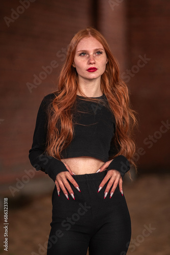 Portrait of a young beautiful red-haired girl in dark clothes in a low key.
