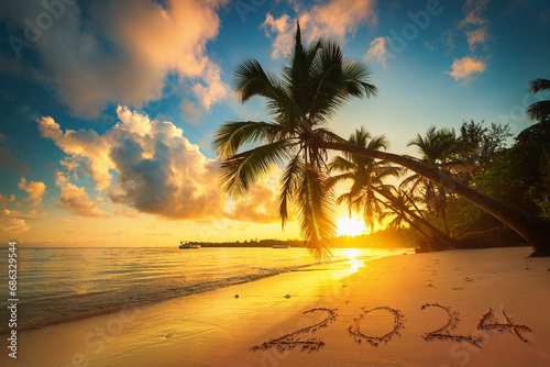 Happy New Year 2024 concept lettering on the beach sand of exotic caribbean island  beautiful sea sunrise with palm trees