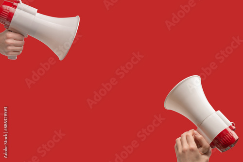 Megaphone in woman hands on a red background.