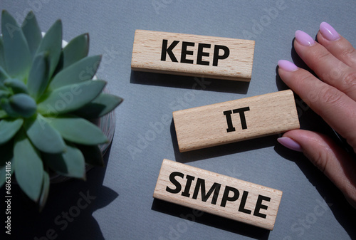 Keep it Simple symbol. Concept words Keep it Simple on wooden blocks. Businessman hand. Beautiful grey background with succulent plant. Business and Keep it Simple concept. Copy space.