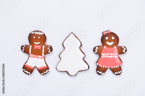 The hand-made eatable gingerbread little men and New Year Tree on white background