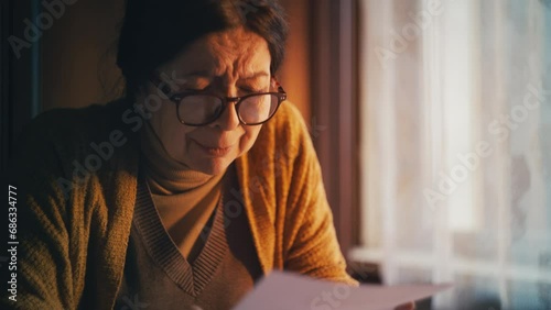 Sad senior woman reading eviction notice and crying, loneliness and poverty photo