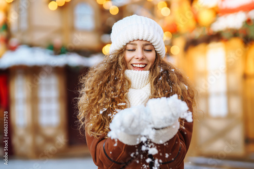 Happy woman having fun at winter Christmas market. A young tourist enjoys the New Year's atmosphere on a sunny winter day. The concept of holiday, relaxation. © maxbelchenko