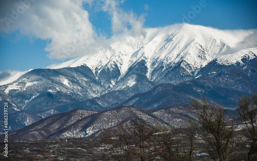 A white cloud covering the snowed mountain peaks of Fagaras Mountains. Deep snow also covers the beech woodlands growing on this harsh landscape. Carpathia, Romania.