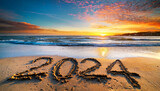 New year, 2024 written in sand on a beach during soft sunset.