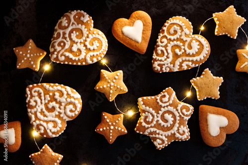 Gingerbreads in the shape of hearts and stars on a black background. Traditional Christmas gingerbrea